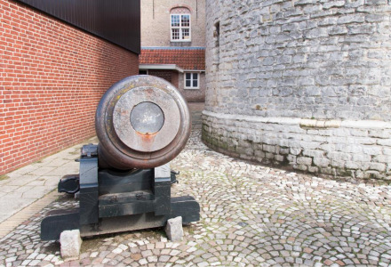 Un antiguo cañón se sitúa en un patio empedrado junto a muros históricos de ladrillo en Vorstenbosch, Países Bajos.