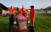 Børn i røde dragter leger på en gammel traktor på FarmCamps Hoeve Sonneclaer, Drenthe, Holland.