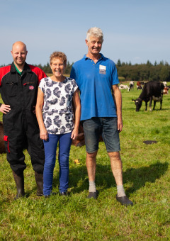 Tres personas posan en un campo junto a vacas en FarmCamps Hoeve Sonneclaer, Drenthe, Países Bajos.