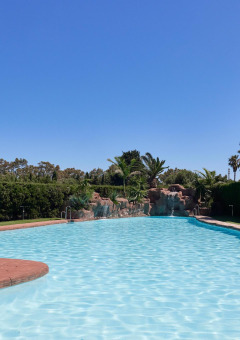 Gran piscina exterior en el parque vacacional TAIGA Tarifa en Andalucía, España, rodeada de vegetación.