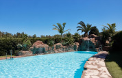 Piscine extérieure avec rochers, palmiers et cascades au parc de vacances TAIGA Tarifa en Andalousie, Espagne.