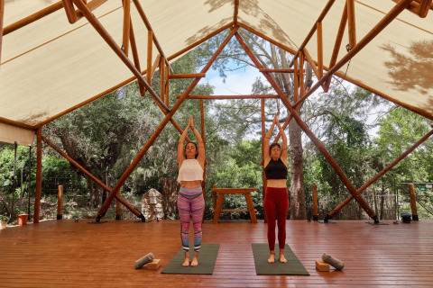 Deux femmes pratiquant le yoga sous une tente ouverte au parc de vacances TAIGA Tarifa en Andalousie, Espagne.