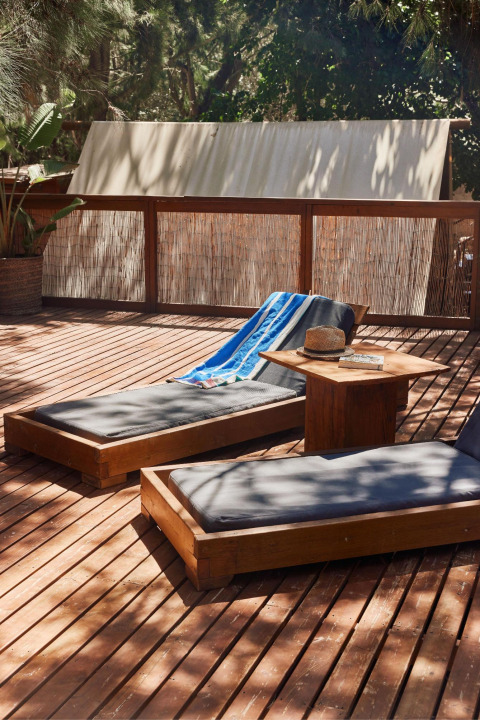 Sunny lounge chairs on a wooden deck at TAIGA Tarifa holiday park in Andalusia, Spain, surrounded by nature.
