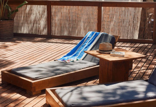 Sonnenliegen auf Holzdeck bei TAIGA Tarifa Ferienpark in Andalusien, Spanien, im Grünen gelegen.