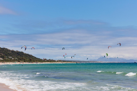 Vue de la plage avec kitesurfeurs au parc de vacances TAIGA Tarifa en Andalousie, Espagne, mer turquoise.