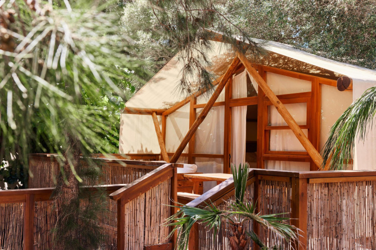 Glamping-hut met houten frame en bamboe omheining bij TAIGA Tarifa vakantiepark in Andalusië, Spanje.