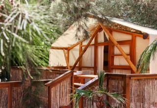 Wood-framed glamping cabin with bamboo fence at TAIGA Tarifa holiday park in Andalusia, Spain.