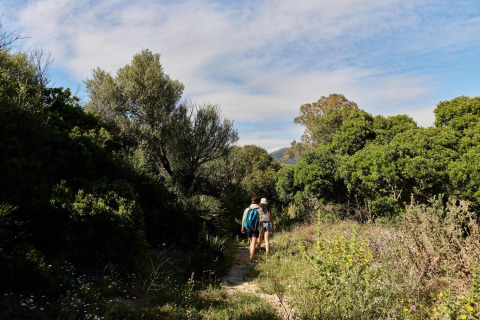 Zwei Personen wandern auf einem naturbelassenen Pfad im Ferienpark TAIGA Tarifa in Andalusien, Spanien.
