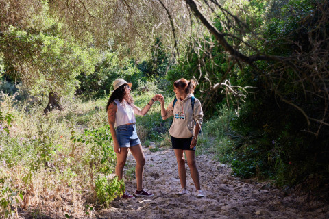 Zwei Frauen wandern durch die Natur in der Nähe von Tarifa, Cádiz, Andalusien, Spanien, umgeben von Grün.