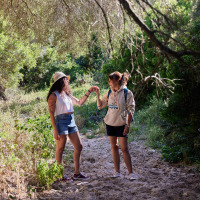Dos mujeres caminan por la naturaleza cerca de Tarifa, Cádiz, Andalucía, España, rodeadas de vegetación verde.