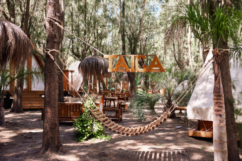 Holzhängematte und Tipis im Ferienpark TAIGA Tarifa umgeben von Bäumen in Andalusien, Spanien.