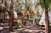 Houten hangmat en tipitenten in TAIGA Tarifa vakantiepark, omringd door bomen in Andalusië, Spanje.
