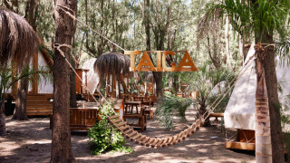 Houten hangmat en tipi-tenten bij TAIGA Tarifa vakantiepark omgeven door bomen in Andalusië, Spanje.