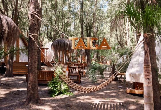 Træhængeseng og tipi-telte i ferieparken TAIGA Tarifa omringet af træer i Andalusien, Spanien.