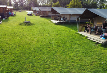 Tenda safari al Camping de Regenboog in Repubblica Ceca con famiglie, prato verde e paesaggio naturale.