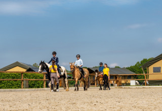 Kinderen leren paardrijden met begeleiders bij FarmCamps Holzik Stables in Overijssel, Nederland.