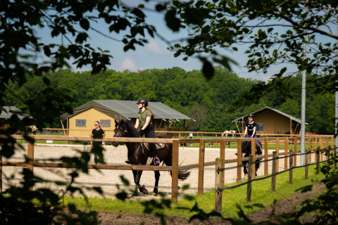Children having horseback riding lessons at FarmCamps Holzik Stables holiday park in Overijssel, Netherlands.