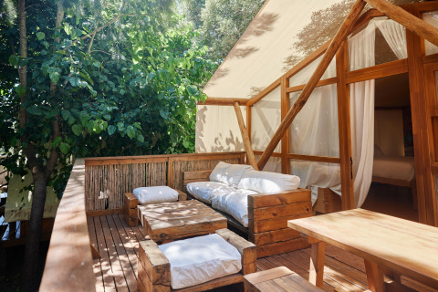 Udendørs terrasse med komfortable træmøbler og hvidt stof på Glamping Luxury Tent La Cala, TAIGA Tarifa, Spanien.