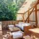 Udendørs terrasse med komfortable træmøbler og hvidt stof på Glamping Luxury Tent La Cala, TAIGA Tarifa, Spanien.