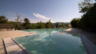 Piscina infinita en Camping Podere Sei Poorte en Marche, Italia, rodeada de naturaleza y colinas verdes.