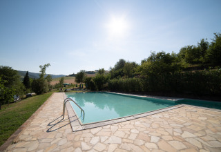 Piscina soleggiata al Camping Podere Sei Poorte, un villaggio turistico immerso nel verde nelle Marche, Italia.