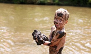 Un niño sonriente juega cubierto de barro junto al río cerca de Enschede, Overijssel, Países Bajos.