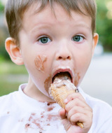 Niño pequeño comiendo un helado con chocolate por la cara y camiseta, foto cerca de Enschede, Overijssel, Países Bajos.