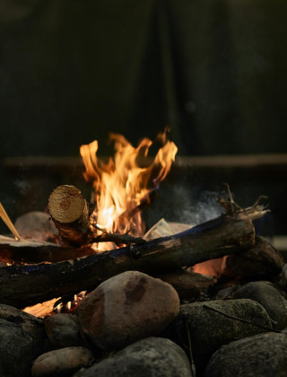 Hoguera con troncos ardiendo rodeada de piedras en FarmCamps Holzik Stables en Overijssel, Países Bajos.