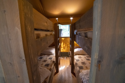 Vista interior de una tienda Safari Lodge con literas de madera en Camping Podere Sei Poorte en Italia.