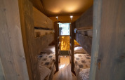 Vista interior de una tienda Safari Lodge con literas de madera en Camping Podere Sei Poorte en Italia.