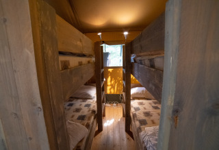 Vista interior de una tienda Safari Lodge con literas de madera en Camping Podere Sei Poorte en Italia.