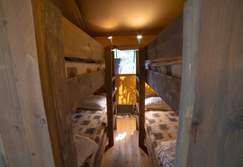 Indvendig udsigt af Safari Lodge telt med køjesenge og træinteriør på Camping Podere Sei Poorte i Italien.