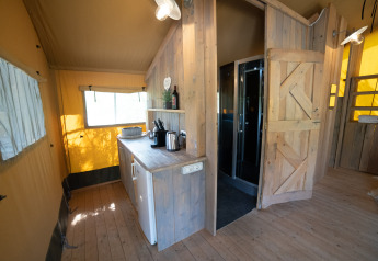 Interni di una tenda Safari Lodge con bagno privato e arredi in legno al Camping Podere Sei Poorte, Italia.