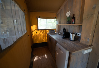 Cocina en una tienda safari con encimera de madera, hervidor y cafetera en Podere Sei Poorte, Italia.
