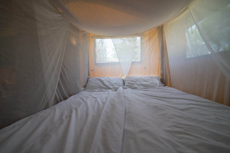 Innenansicht eines Safarizeltes mit Doppelbett und Moskitonetz bei Camping Podere Sei Poorte in Italien.