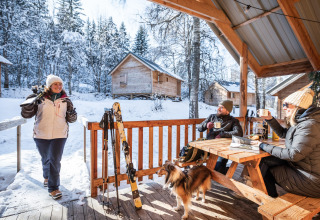 Winterurlaub im Les Chalets Huttopia de Bozel mit Menschen, die heiße Getränke im verschneiten Chalet genießen.