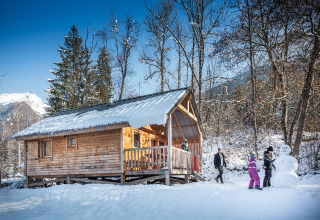 Famiglia costruisce un pupazzo di neve davanti a uno chalet a Les Chalets Huttopia de Bozel, in Francia.