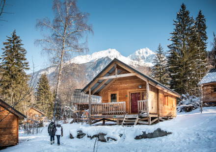 Houten chalet in besneeuwde bergen bij Chalet Montana, Les Chalets Huttopia de Bozel, Frankrijk, blauwe lucht.