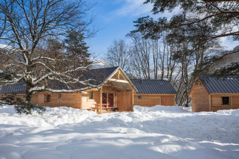 Houten chalets bij Les chalets Huttopia de Bourg-St-Maurice in Frankrijk, in een besneeuwd winterlandschap.