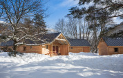 Chalets en bois à Les chalets Huttopia de Bourg-St-Maurice, France, entourés de neige et d'arbres en hiver.