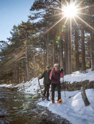 Excursionistas caminando junto a un río nevado cerca de Val-Des-Près, Provenza-Alpes-Costa Azul, Francia.