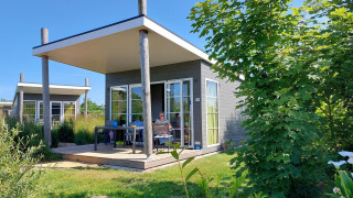 Lodge Comfort con terraza moderna, rodeada de jardín verde bajo el sol, alojamiento apto para perros.