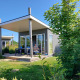 Komfort Lodge med moderne design og terrasse, omgivet af grøn have, solrig dag, hunde tilladt.