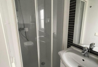Salle de bain avec douche et lavabo dans Comfort Lodge au Kompas Camping Westende, Belgique, chiens admis.