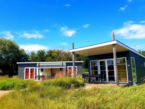 To moderne Comfort Lodge-hytter omgivet af frodige græsarealer under en klar blå himmel, hunde tilladt