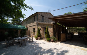 Buiten zitruimte en stenen gebouw bij Camping Podere Sei Poorte, Marche, Italië op zonnige dag.