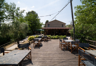 Buitenterras met tafels en stoelen bij Camping Podere Sei Poorte vakantiepark in Marche, Italië.
