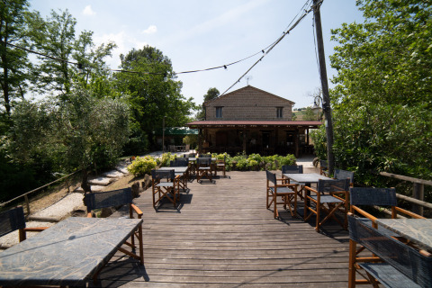 Outdoor terrace with tables and chairs at Camping Podere Sei Poorte holiday park in Marche, Italy.