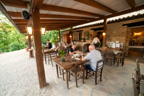 Udendørs restaurant på Camping Podere Sei Poorte i Marche, Italien, med gæster, der nyder maden.