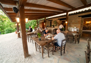 Buiten eetgedeelte bij Camping Podere Sei Poorte in Marche, Italië, met gasten aan tafel.